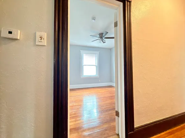 a view of a hallway with wooden floor and a bathroom