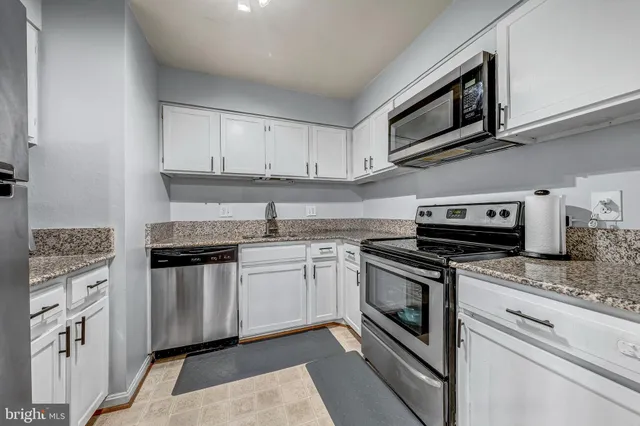 a kitchen with granite countertop cabinets stainless steel appliances and a sink