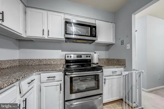 a kitchen with granite countertop a stove top oven microwave and cabinets