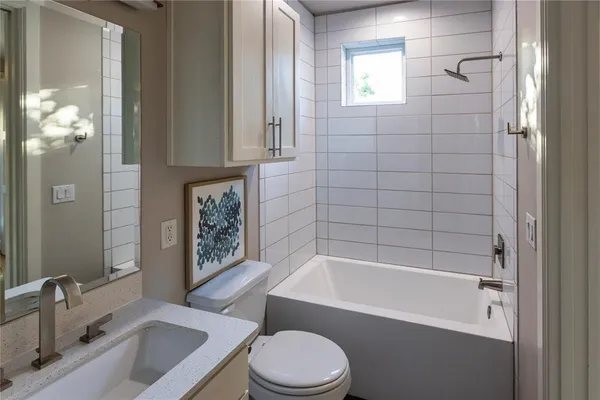 a bathroom with a sink a toilet a mirror a bathtub and shower