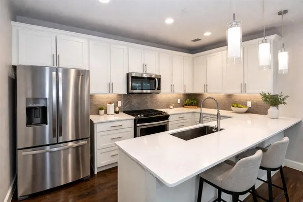 a kitchen with a refrigerator a stove a sink and white cabinets