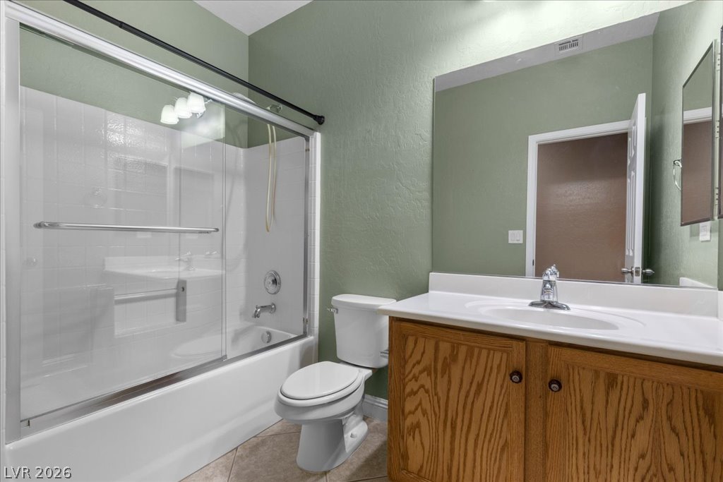 2627 Dirleton Place Henderson, NV 89044 - Photo 26 of 42 A well-appointed bathroom features a bathtub with a clear glass enclosure and a vanity with a white countertop.