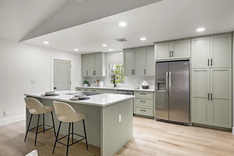 a kitchen with stainless steel appliances granite countertop a sink a stove a refrigerator and island with wooden floor