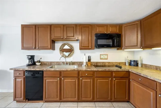 a kitchen with granite countertop a sink a stove a microwave and wooden cabinets