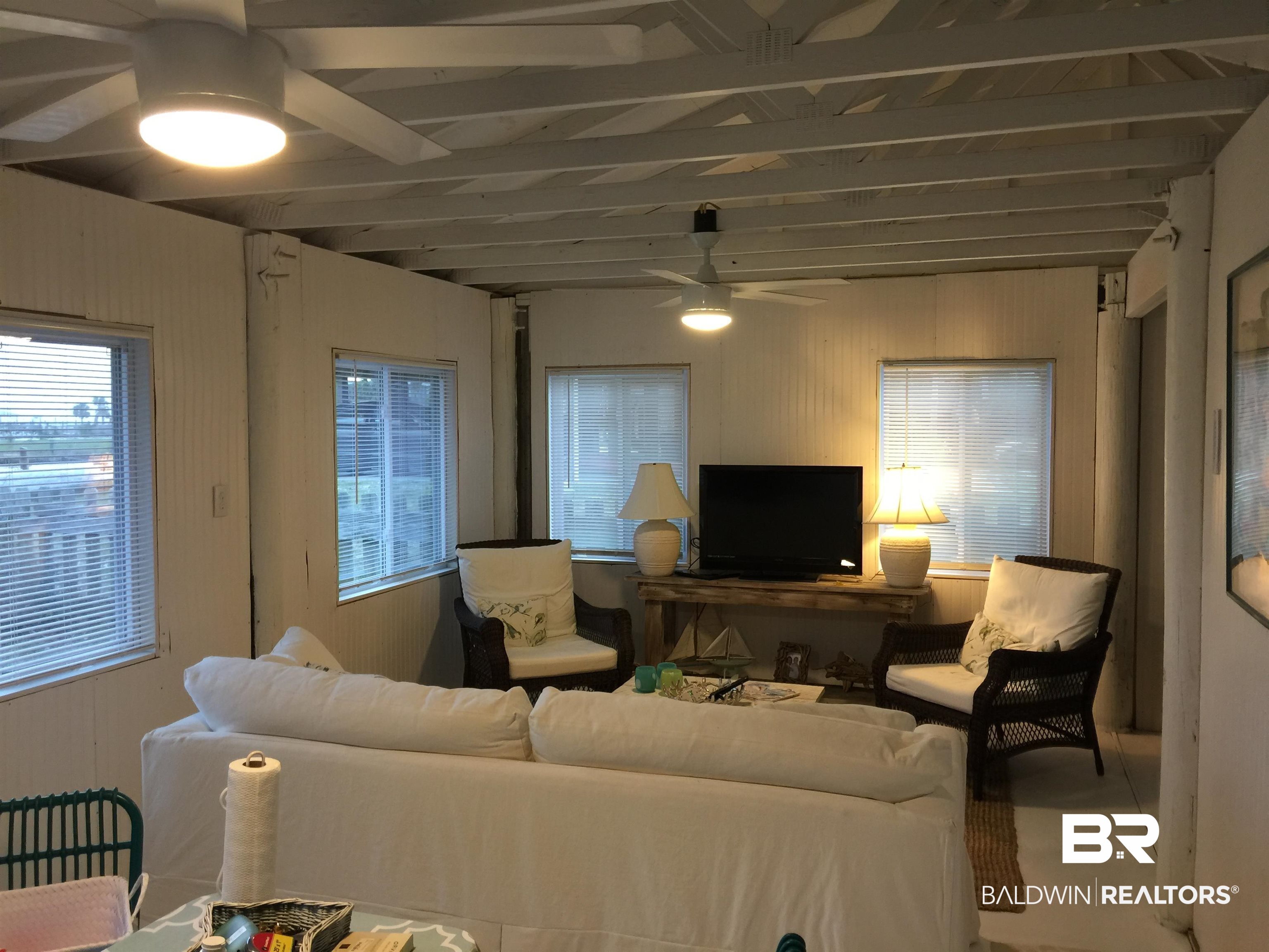 2412 Choctaw Road Gulf Shores, AL 36542 - Photo 10 of 16 Living room with a ceiling fan, wood walls, and beamed ceiling