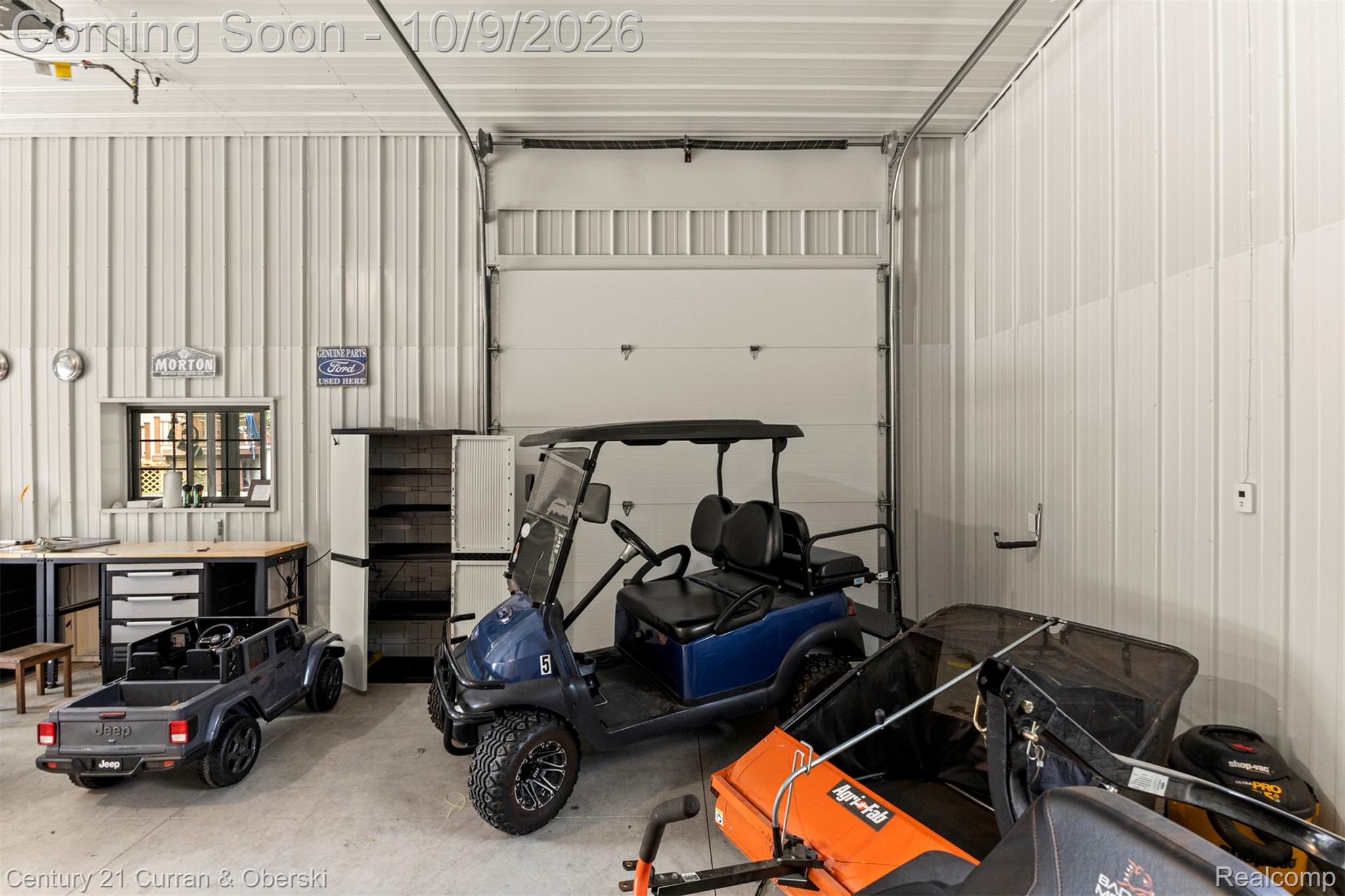 43040 Willis Road Belleville, MI 48111 - Photo 43 of 65 Industrial-style garage featuring corrugated metal walls, a concrete floor, a window with grilles, and a workbench with built-in storage
