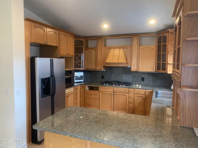 a kitchen with stainless steel appliances granite countertop a refrigerator and a stove top oven