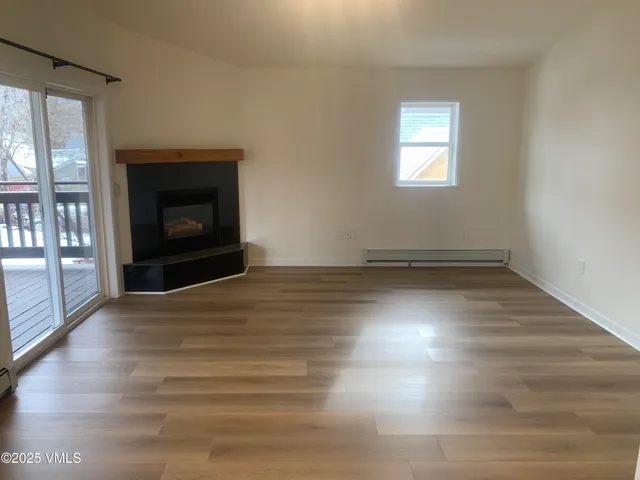a view of empty room with wooden floor and fireplace