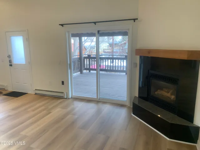 a view of an empty room with wooden floor and a fireplace