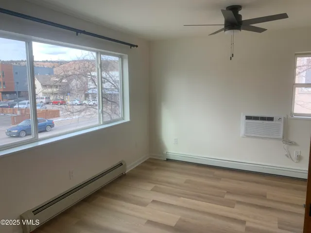 an empty room with wooden floor and windows