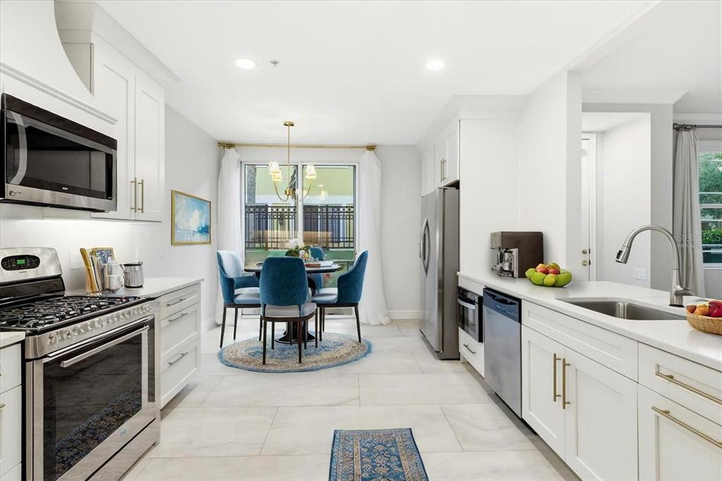 6536 Moorings Point Circle, Unit 101 Lakewood Ranch, FL 34202 - Photo 17 of 48 a kitchen with stainless steel appliances granite countertop a stove top oven a sink dishwasher a dining table and chairs with wooden floor