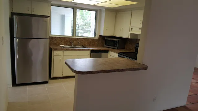 a kitchen with granite countertop stainless steel appliances a refrigerator microwave and sink