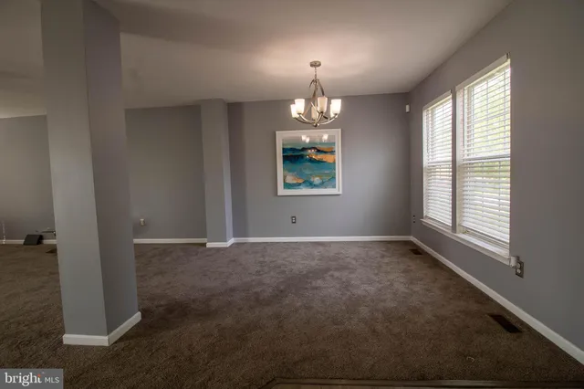 an empty room with chandelier and windows