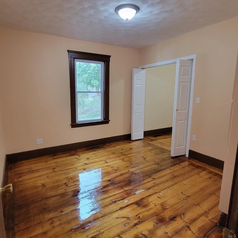 111 Rodney Street, Unit 1 Worcester, MA 01605 - Photo 4 of 9 a view of an empty room with wooden floor and a window