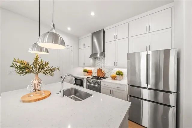 a kitchen with stainless steel appliances a refrigerator a sink a table and chairs