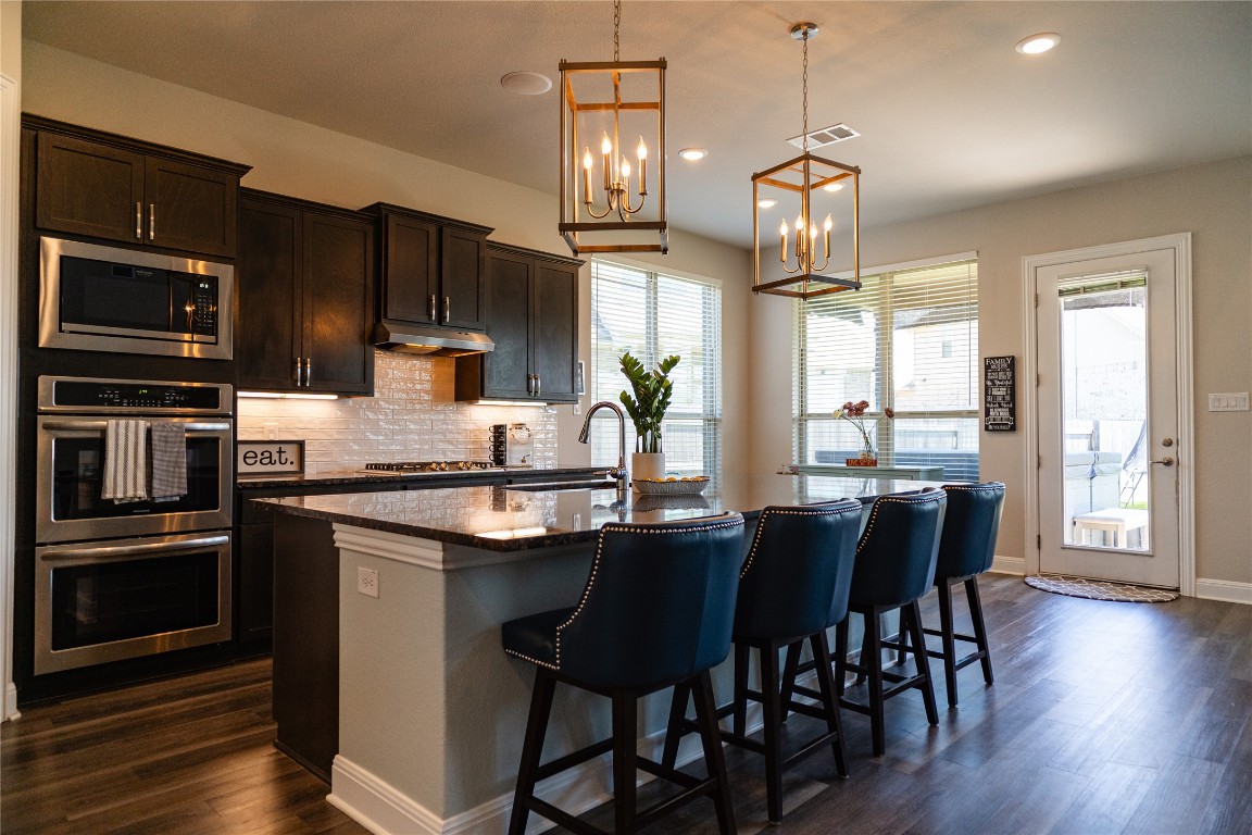 2616 Pine Branch Road Leander, TX 78641 - Photo 7 of 37 a kitchen with stainless steel appliances wooden floor dining table and chairs