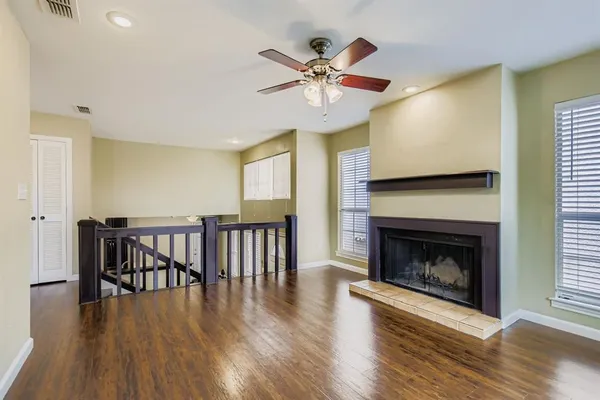 a view of a livingroom with fireplace wooden floor and a ceiling fan