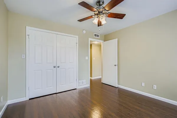 an empty room with wooden floor a ceiling fan and closet