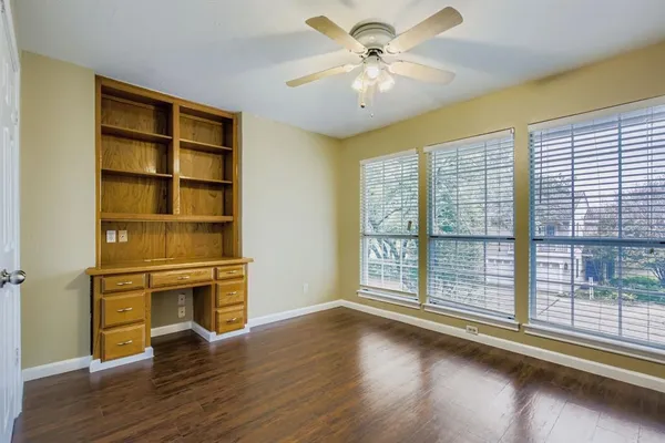a view of empty room with wooden floor and fan
