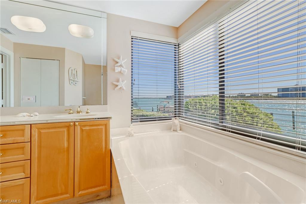 400 La Peninsula Boulevard, Unit 404 Naples, FL 34113 - Photo 13 of 19 a bathroom with a granite countertop sink and a bathtub