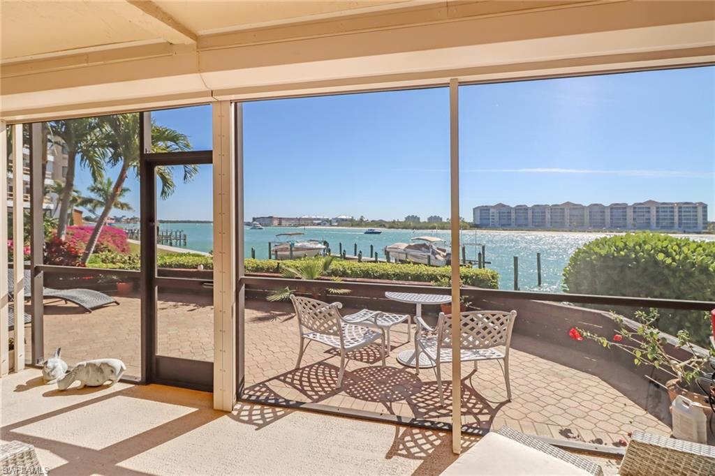 400 La Peninsula Boulevard, Unit 404 Naples, FL 34113 - Photo 5 of 19 a living room with a table and chairs next to a window