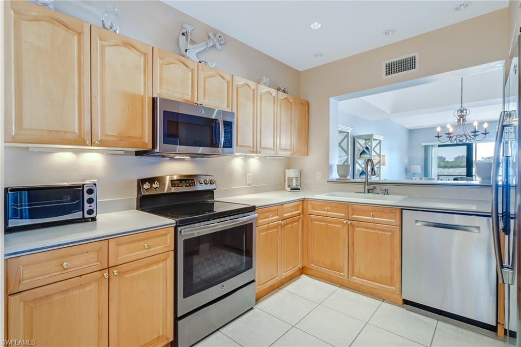 400 La Peninsula Boulevard, Unit 404 Naples, FL 34113 - Photo 8 of 19 a kitchen with granite countertop white cabinets white stainless steel appliances and a sink