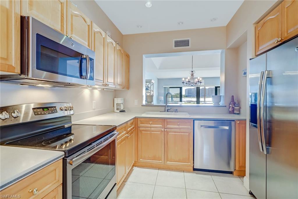 400 La Peninsula Boulevard, Unit 404 Naples, FL 34113 - Photo 9 of 19 a kitchen with stainless steel appliances granite countertop a refrigerator and a sink