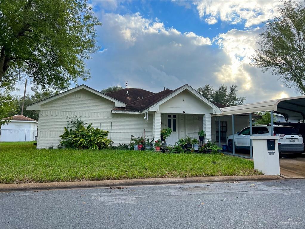 a view of a house with a yard plants and large tree