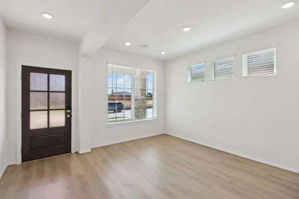 a view of an empty room with a window and wooden floor
