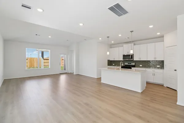 a view of kitchen with stainless steel appliances granite countertop white cabinets and wooden floor