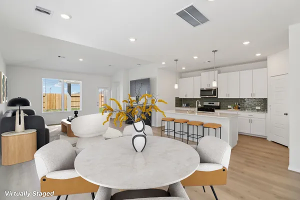 a view of kitchen with granite countertop refrigerator and white cabinets