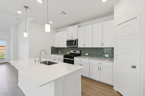 a kitchen with stainless steel appliances a sink and a wooden floor
