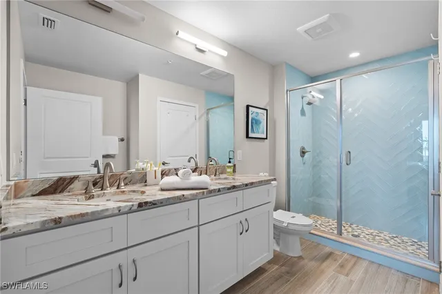 a bathroom with a double vanity sink toilet mirror and shower