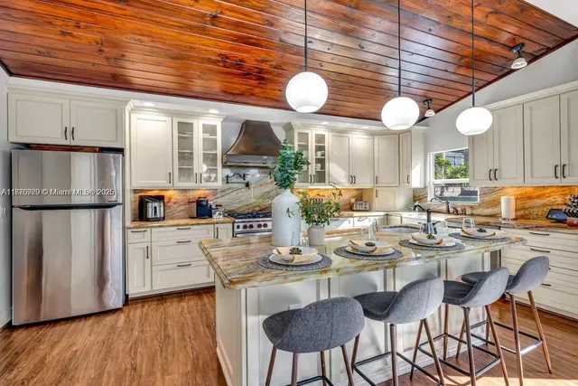 a kitchen with stainless steel appliances granite countertop a stove top oven a dining table and chairs with wooden floor