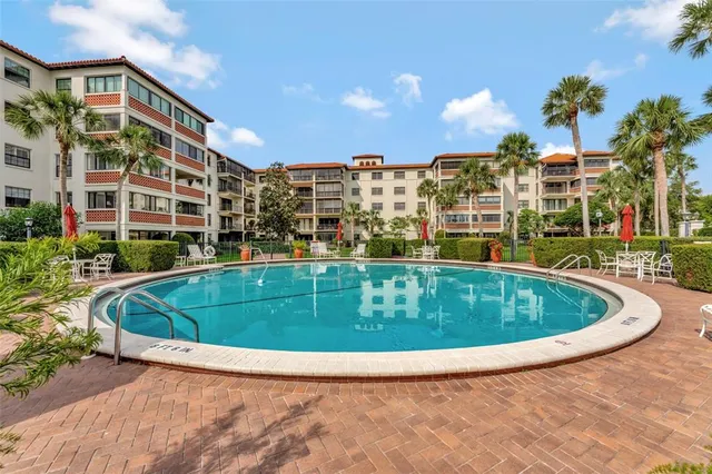 a view of swimming pool with outdoor seating and buildings in the background
