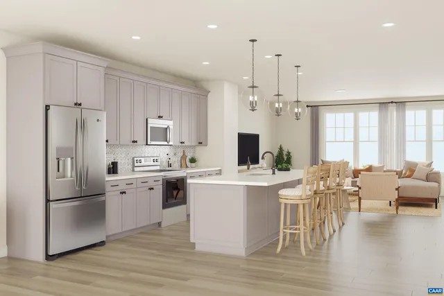 a kitchen with stainless steel appliances a stove a refrigerator a kitchen island and couches with wooden floor