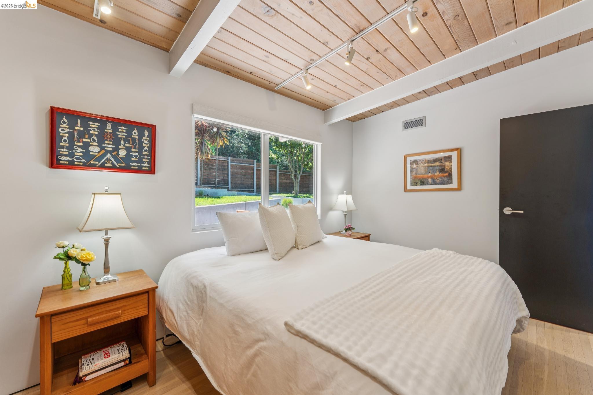 6733 Snake Road Oakland, CA 94611 - Photo 18 of 57 a bedroom with a bed and a lamp on dresser