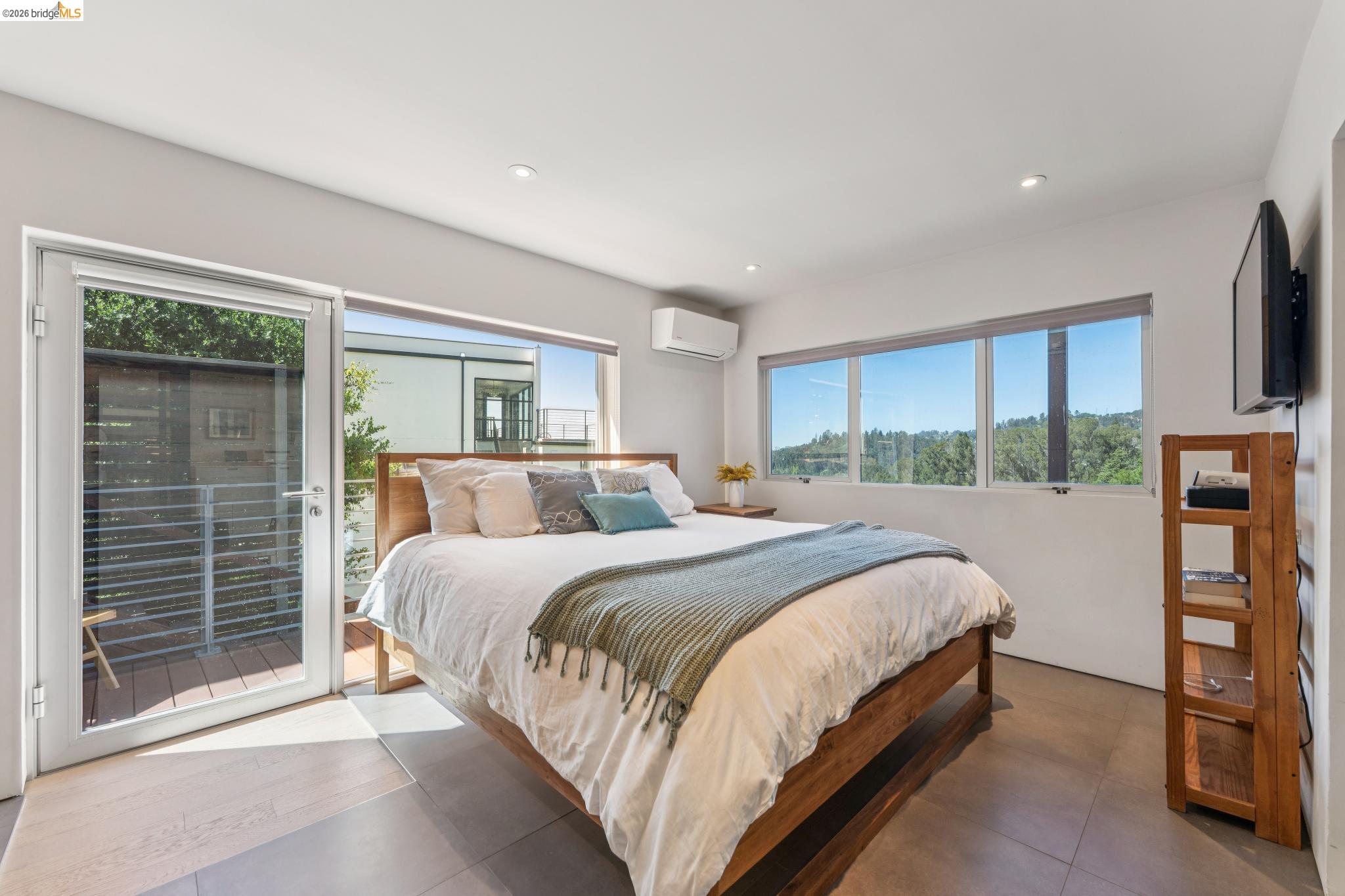 6733 Snake Road Oakland, CA 94611 - Photo 27 of 57 a bedroom with a large bed and a flat tv screen