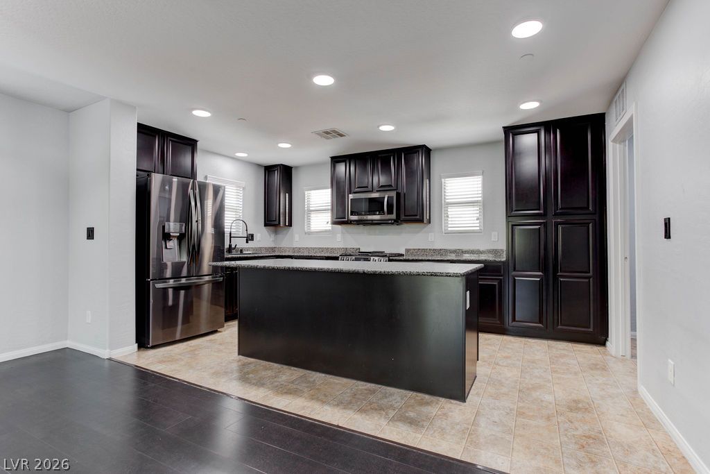 7724 Vibrant Thread Court Las Vegas, NV 89149 - Photo 7 of 43 A contemporary kitchen showcasing dark wood cabinetry, granite countertops, and modern stainless steel appliances.