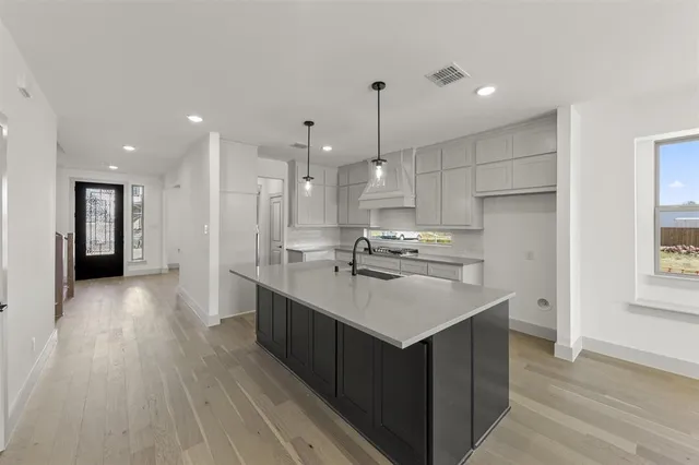 a kitchen with stainless steel appliances granite countertop a sink a stove and a wooden floors