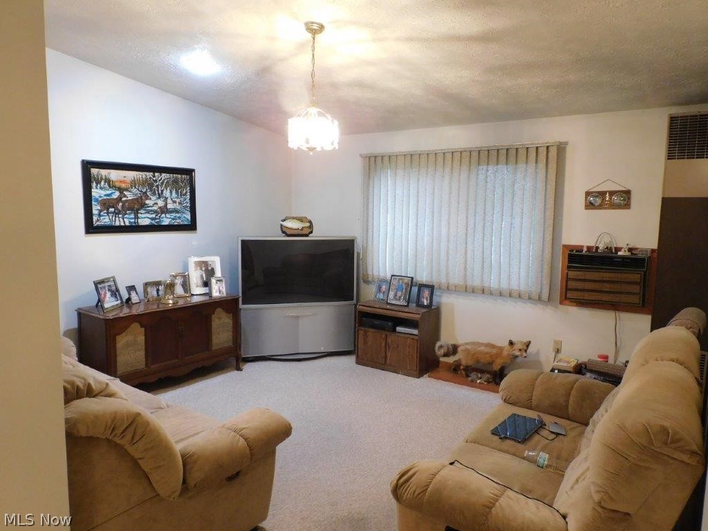 5853 Shepard Road Ashtabula, OH 44004 - Photo 23 of 27 Living room featuring a textured ceiling, light carpet, a chandelier, and lofted ceiling