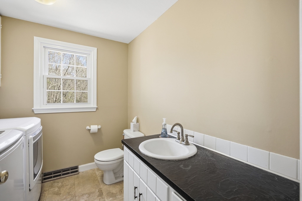 200 Nashua Road Groton, MA 01450 - Photo 19 of 41 a bathroom with a granite countertop toilet a sink and a window