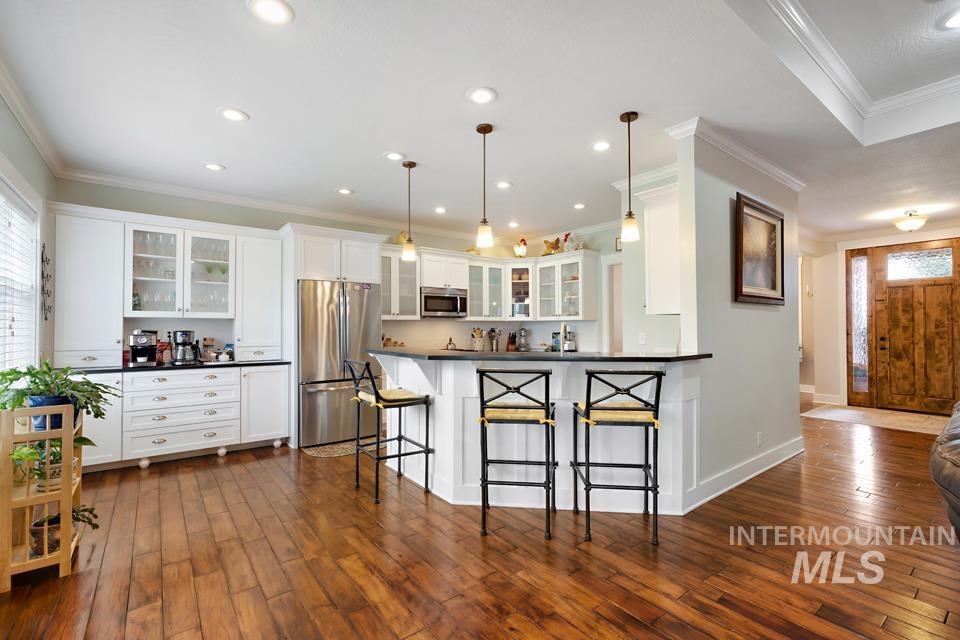 8271 Washoe Road Fruitland, ID 83619 - Photo 16 of 29 Spacious kitchen featuring white cabinetry, stainless steel appliances, dark countertops, and a peninsula with pendant lighting
