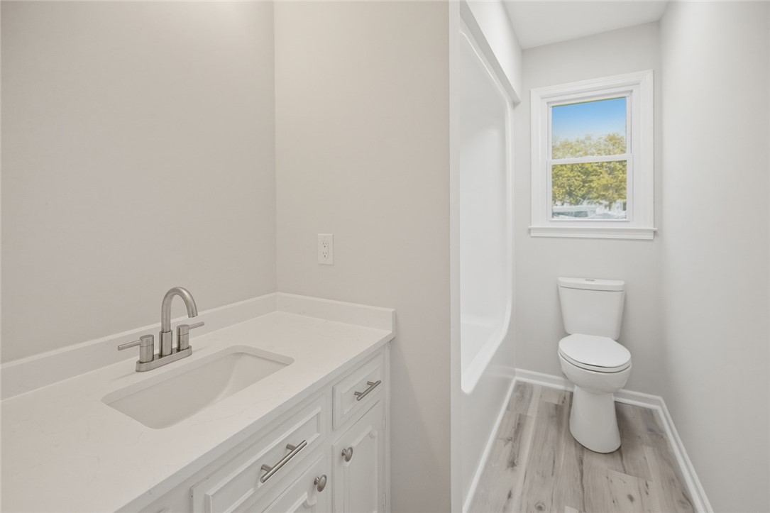 902 Cherokee Road Pelzer, SC 29669 - Photo 10 of 38 A well-lit bathroom features a vanity with a sleek sink and a commode with a window above.