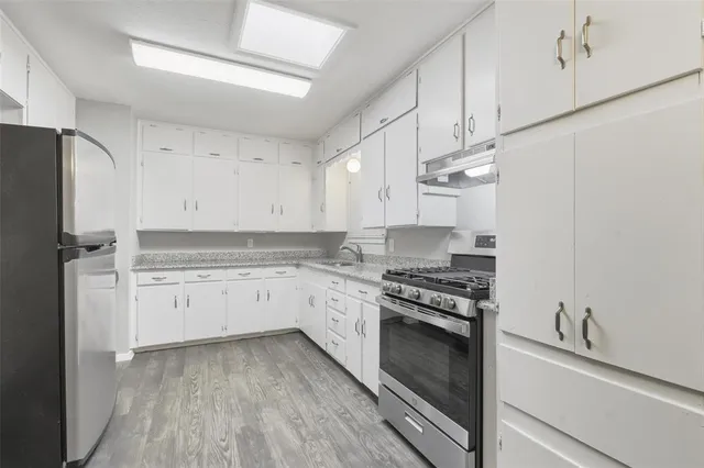 a kitchen with granite countertop cabinets stainless steel appliances and wooden floor