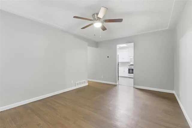 an empty room with wooden floor ceiling fan and windows