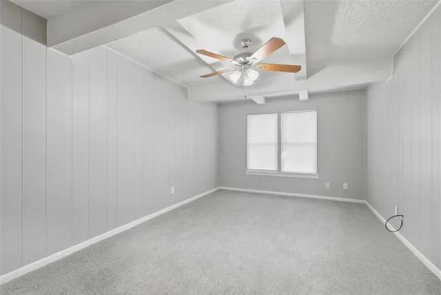 an empty room with windows and fan