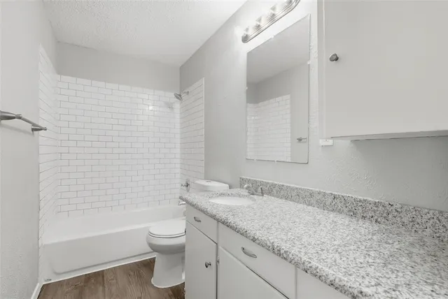 a bathroom with a granite countertop sink a toilet and bathtub