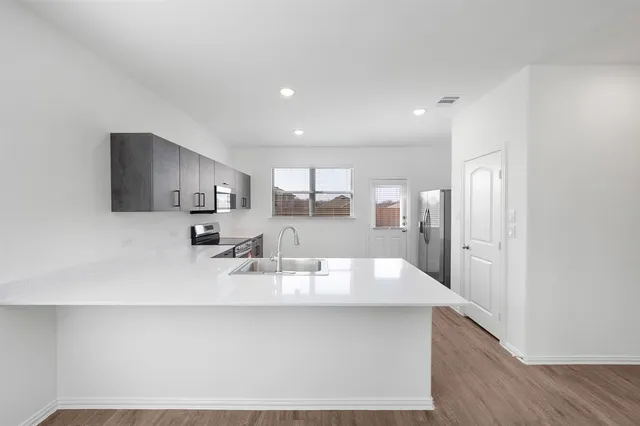 a large white kitchen with kitchen island a sink stainless steel appliances and cabinets