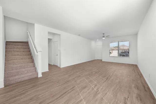 a view of an empty room with wooden floor and stairs